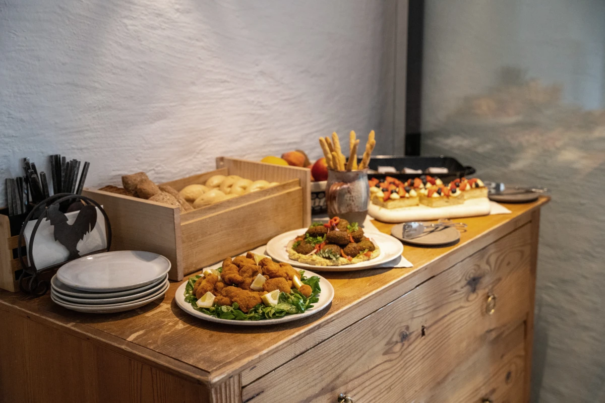 Buffet auf Holztisch: frittierte Kroketten auf Salat mit Zitronenscheiben, Brotlaibe und Brotstangen in Gläsern